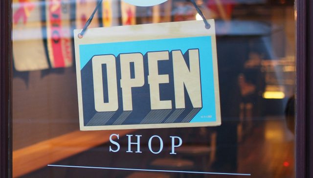Open sign hanging in a small business shop window
